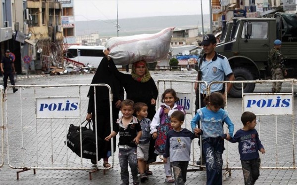 Μία συριακή οικογένεια περνάει δίπλα από ερείπια μετά από μία έκρηξη στην πόλη Ρεχάνλι στη Συρία.