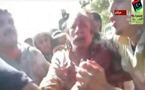Former Libyan leader Muammar Gaddafi, covered in blood, is pulled from  a truck by NTC fighters in Sirte in this still image taken from video footage