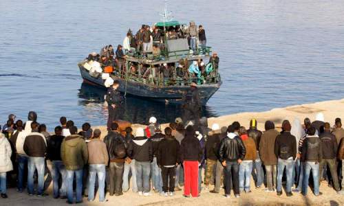 Migrants from North Africa arrive, escorted by Italian Guardia di Finanza, at the southern Italian island of Lampedusa in this March 24, 2011 file picture. Thousands of Eritreans attempt each year to make a trip to reach Europe, fleeing one of Africa's poorest and most isolated nations, a place where army conscription with pitiful pay can last years. Many die on the trek. Probably all of the more than 360 migrants who drowned in a shipwreck near Italy's coast in October 2013 were Eritrean, though many are still unidentified. To match Feature ETHIOPIA-ERITREA/MIGRANTS. REUTERS/Alessandro Bianchi/Files (ITALY - Tags: SOCIETY IMMIGRATION)