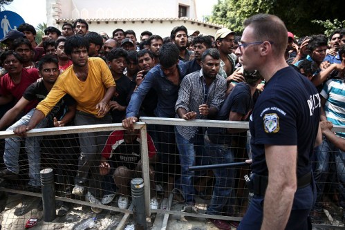 Migrants wait behind a fence for a registration procedure outside a police station at southeastern island of Kos, Monday, Aug. 10, 2015.  Greece's coast guard rescued more than 1,400 migrants in nearly 60 search and rescue operations near several Greek islands in the eastern Aegean Sea over the past three days as the pace of new arrivals increase, authorities said Monday. (AP Photo/Yorgos Karahalis)