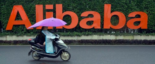A woman rides a bike past the company logo outside the Alibaba Group headquarters in Hangzhou, in eastern China's Zhejiang province on Friday, May 27, 2016.  Alibaba began 17 years ago in the modest living room of a gutsy man with a history of failure. Jack Ma struggled in school, and even Kentucky Fried Chicken refused to hire him. Today, Alibaba is a $15.7 billion e-commerce ecosystem that supports the livelihoods of tens of millions of merchants. Some 423 million shoppers last fiscal year picked through the billion listings that Alibaba's platforms host on any given day. (AP Photo/Ng Han Guan)